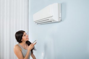 A woman setting the temperature on her ductless AC unit
