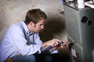 A technician using a screwdriver to access the inside of a heating system