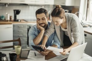 A couple looking at a calculator together with bills on the table