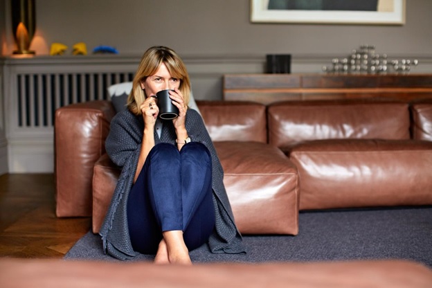 A woman wrapped in a blanket, drinking from a mug