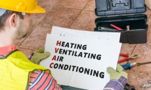 A technician looking at a piece of paper that displays the HVAC acronym