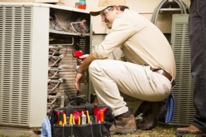 An HVAC technician looking inside a furnace