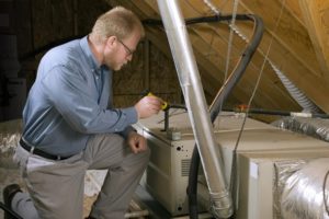 An HVAC technician checking a heating unit in an attic