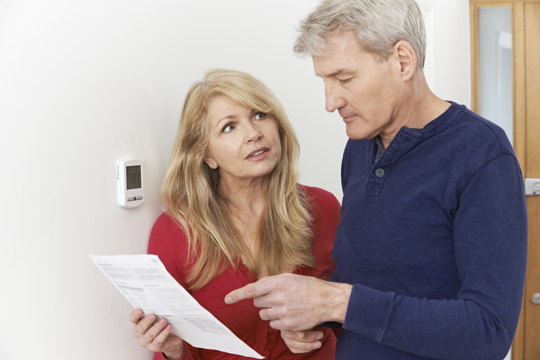 A man and woman looking concerned while reading a bill