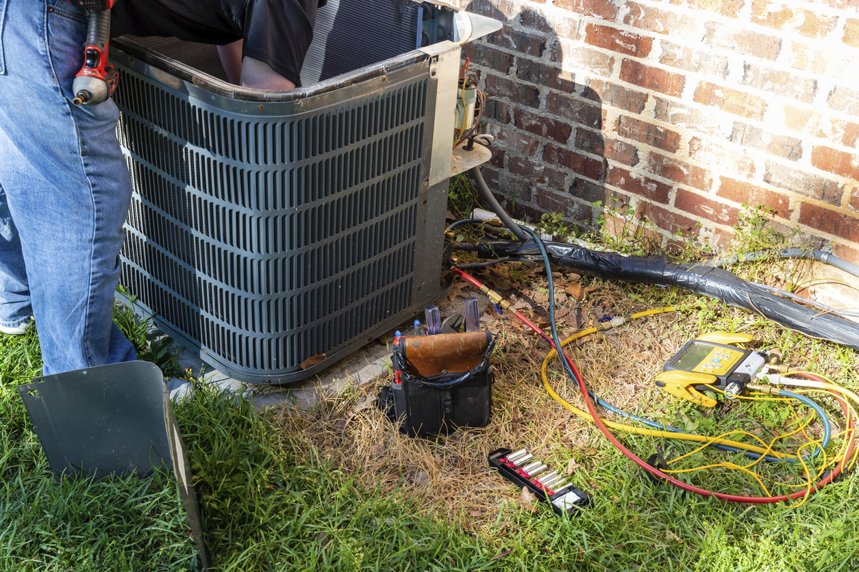 HVAC technician tuning up an outdoor AC unit