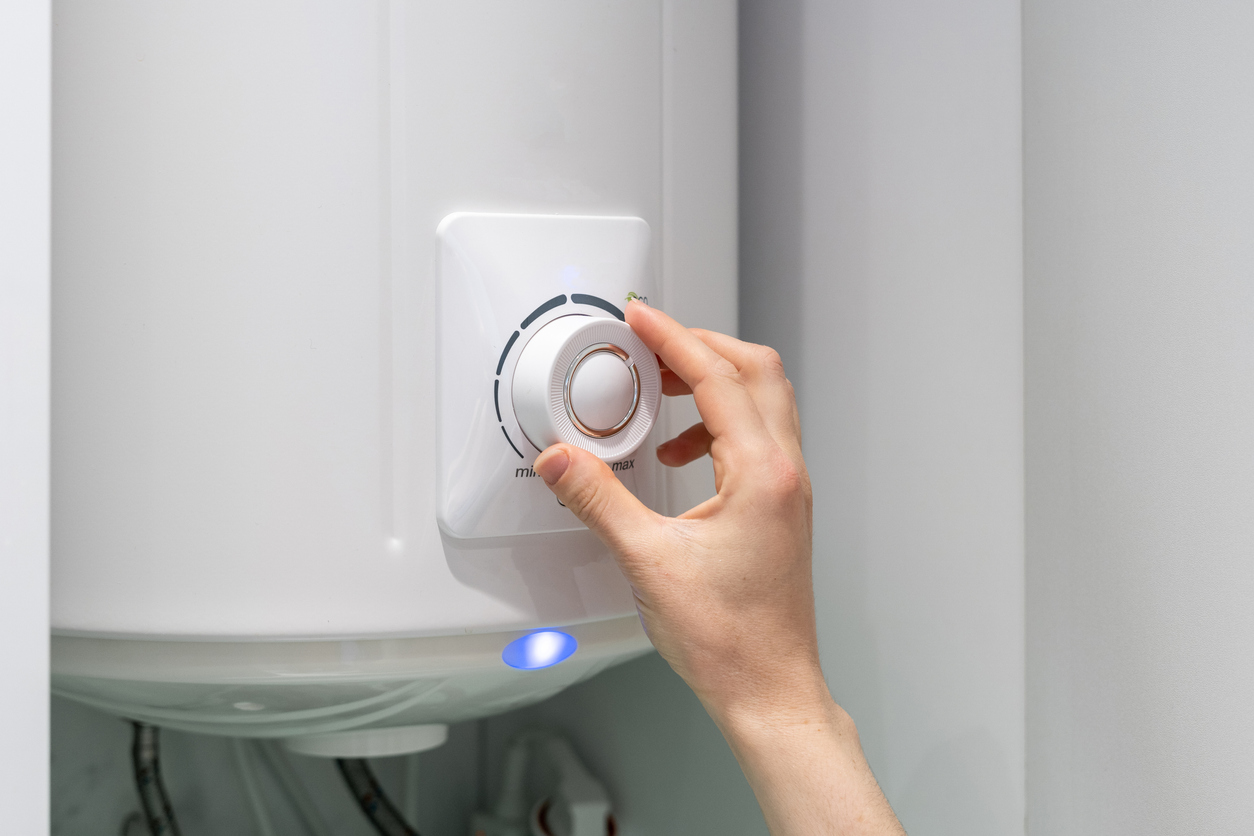 Homeowner’s hand adjusting a boiler’s temperature knob