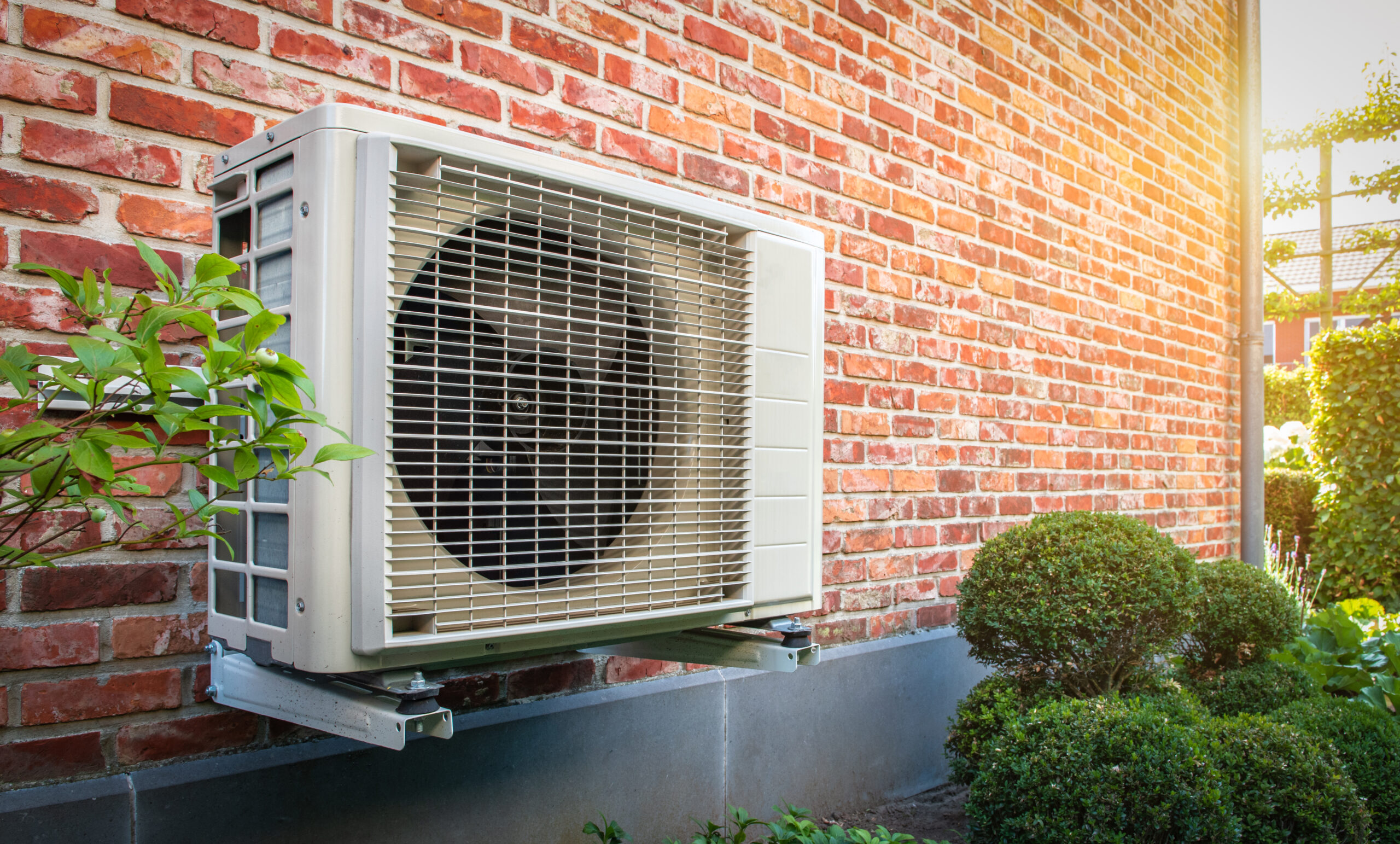 Heat pump mounted on a brick wall of a home
