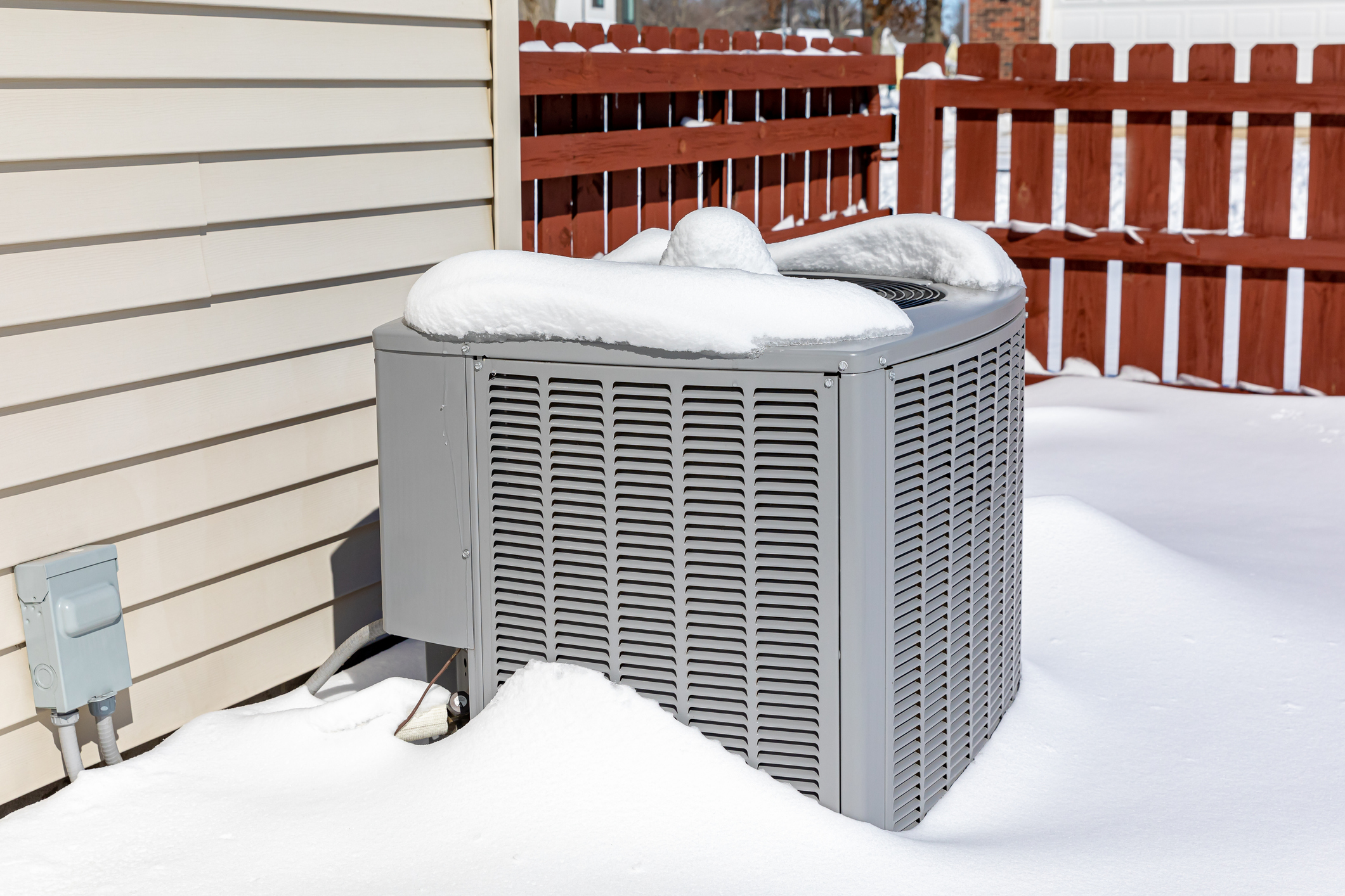 HVAC unit covered in snow outside a North Aurora home