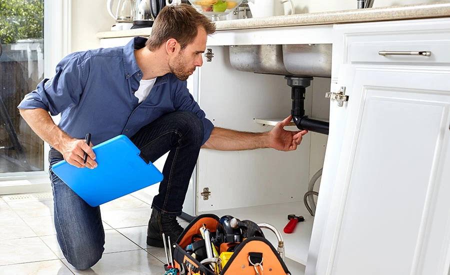 Man fixing plumbing under sink